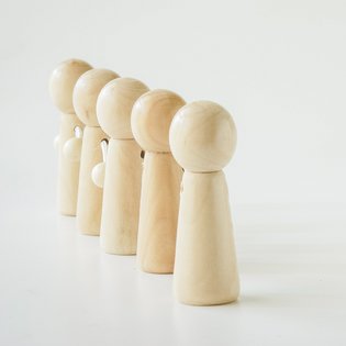 Spielfiguren aus Holz stehen in einer Reihe vor weißem Hintergrund.