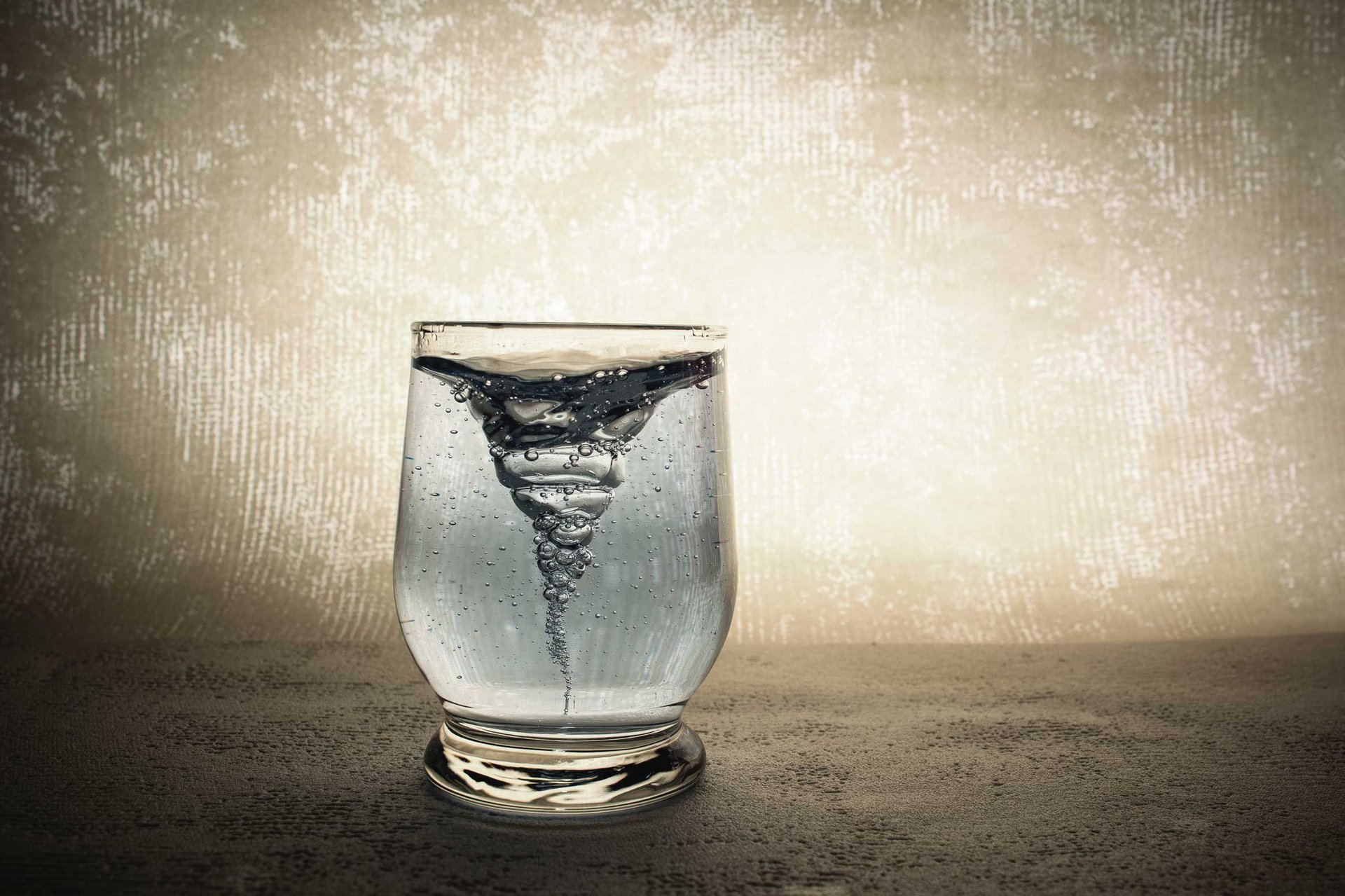 In einem Glas Wasser entwickelt sich ein sprudelnder Strudel. 