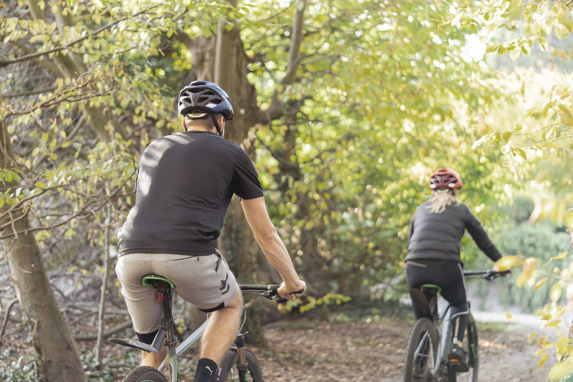 Zwei Personen fahren an der frischen Luft in einem Wald Fahrrad. 