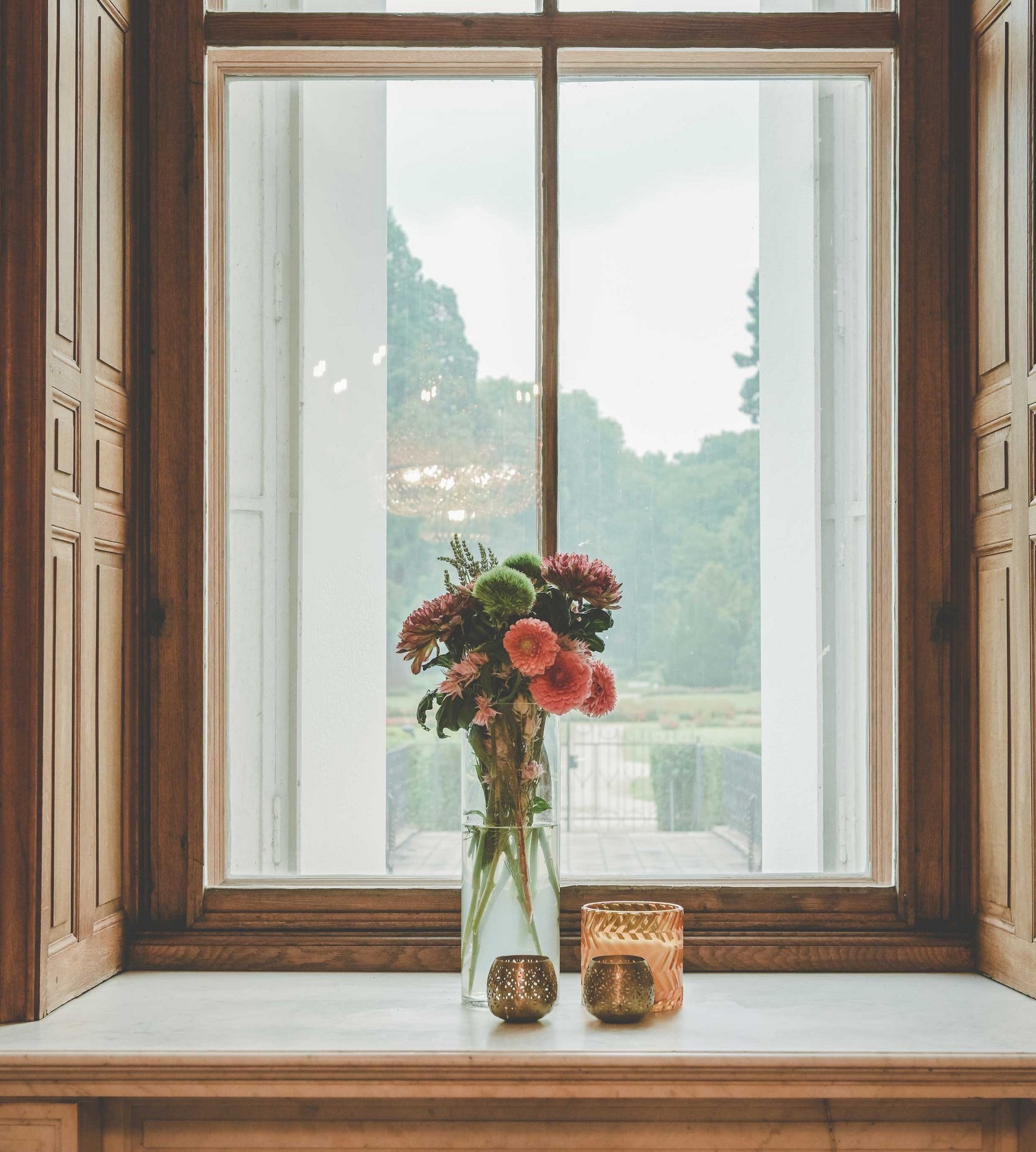 Eine Vase mit frischen Blumen vor einem Fenster.