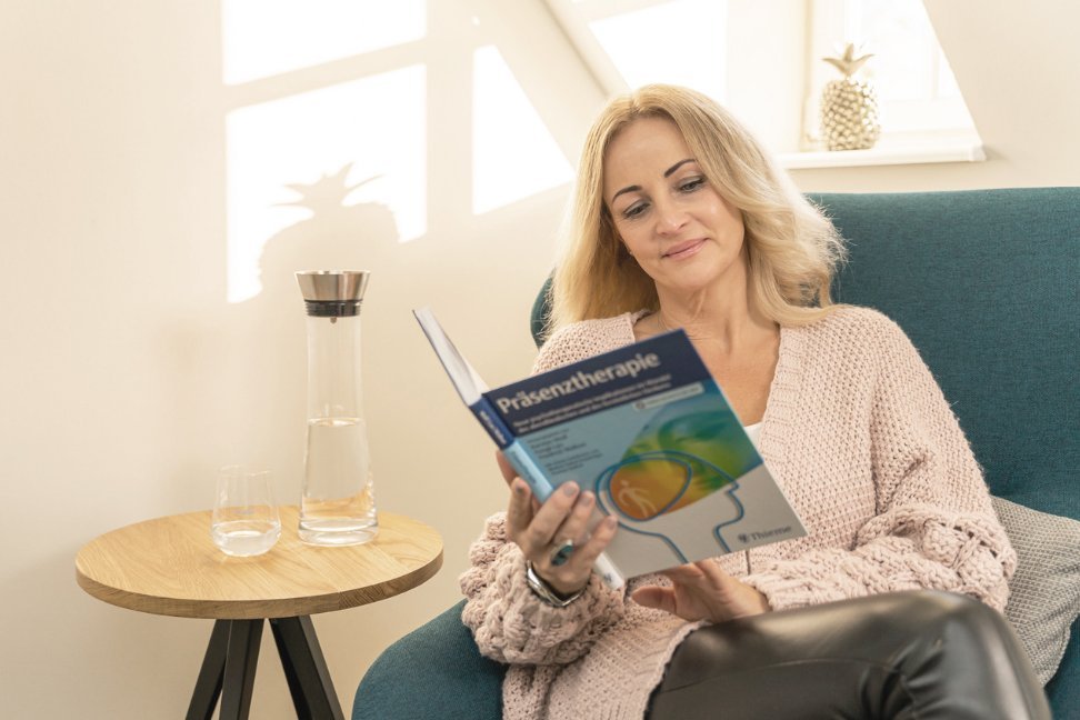 Eine Frau liest ein Buch über Präsenztherapie.