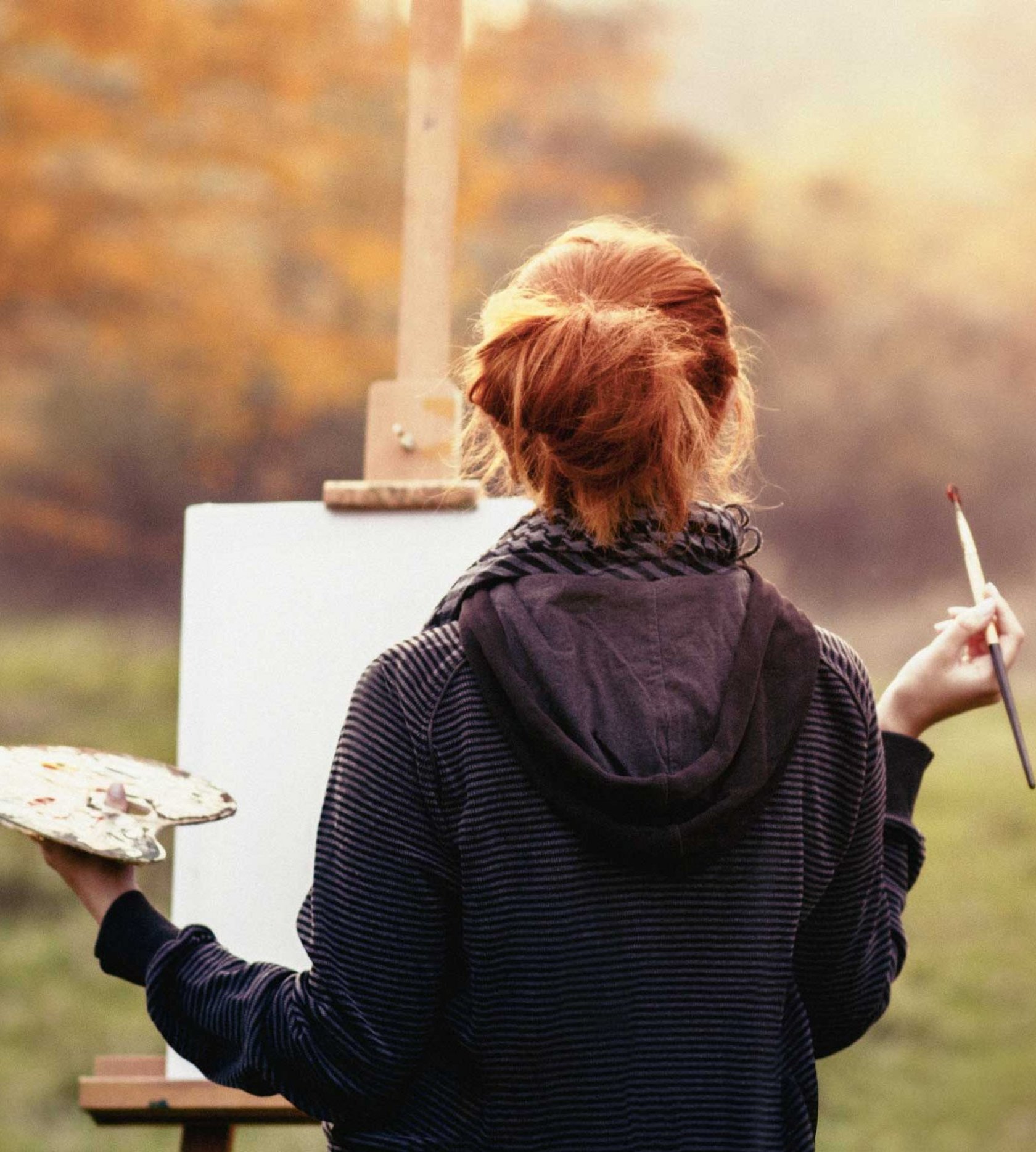 Eine Frau malt in der Natur ein Bild.