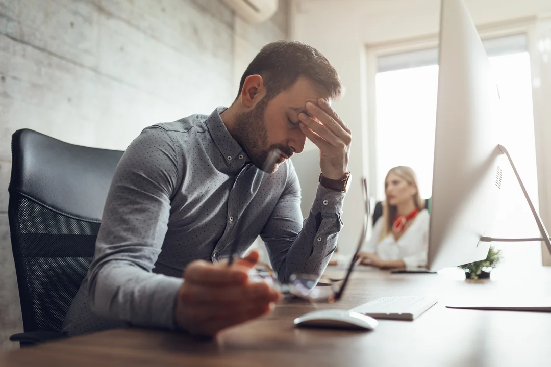 Manager sitzt gestresst an Schreibtisch 1