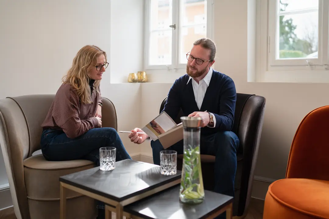beratungsgespraech mann frau buch sessel wohnzimmer