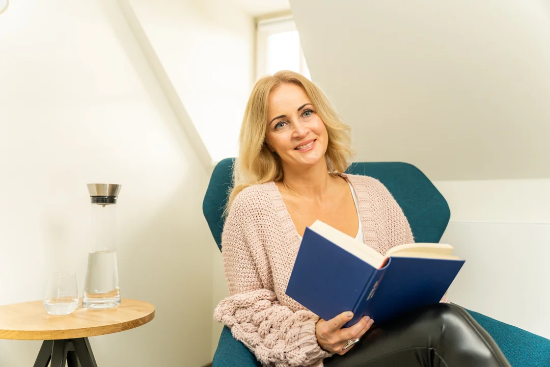 blonde-frau-buch-lesen-sessel-wohnzimmer
