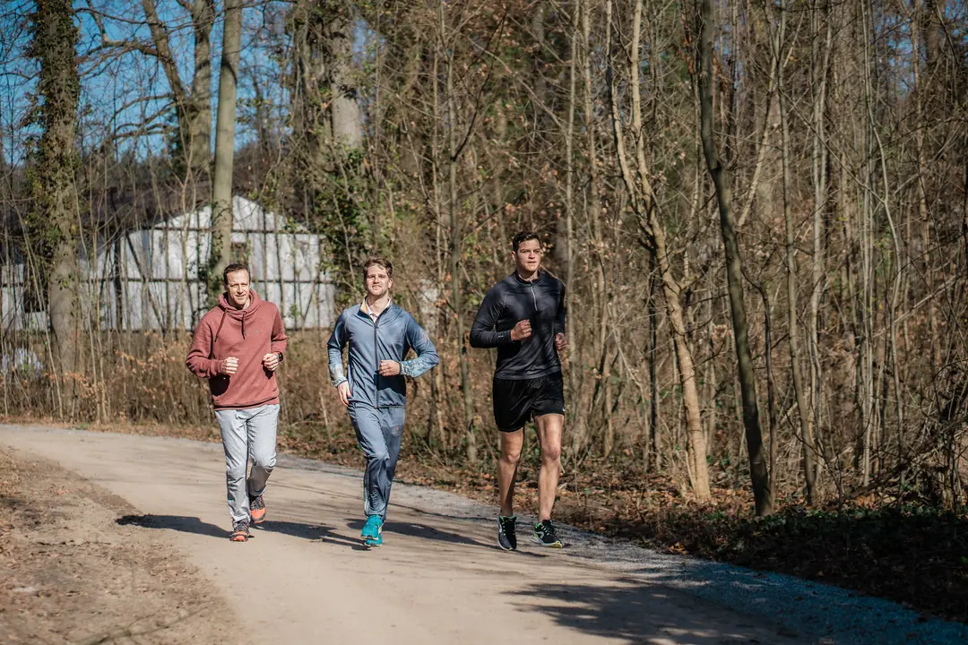 drei maenner joggen waldweg fruehling sport