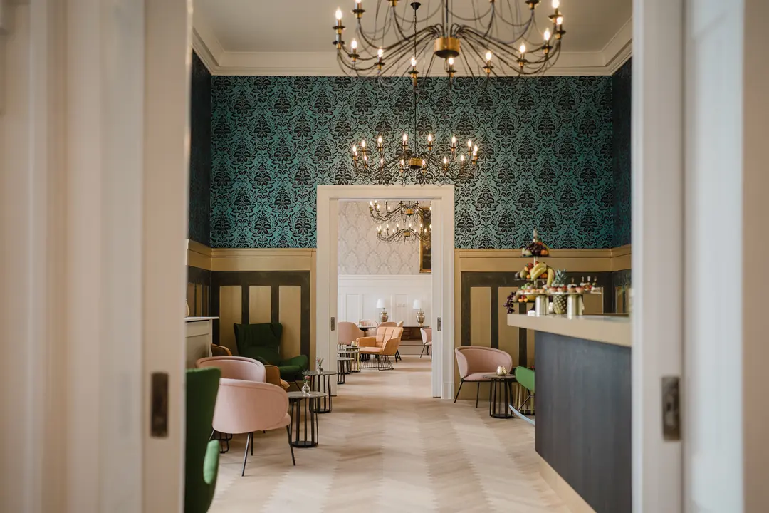 elegante hotellobby kronleuchter gruene tapete samt sessel
