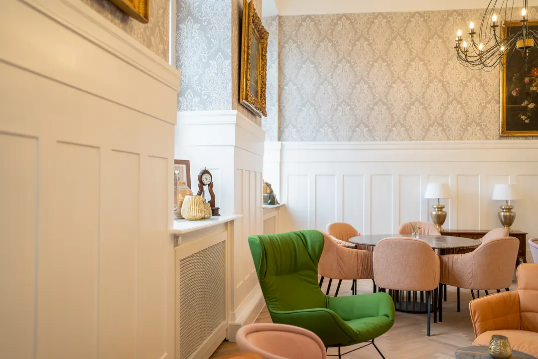 elegantes-cafe-gruene-sessel-kronleuchter-vintage-wandvertaefelung