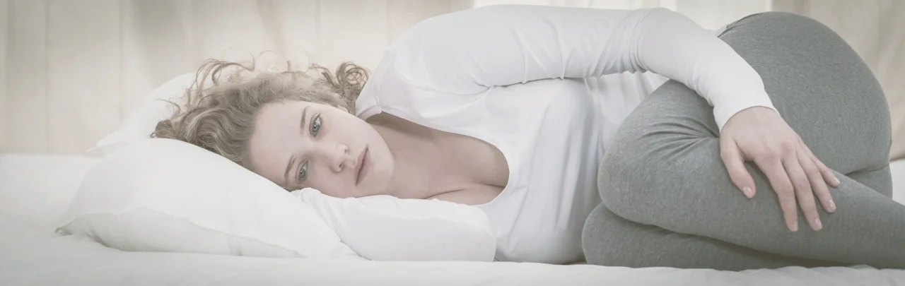 frau liegt im bett traurig