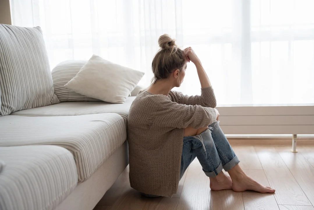 frau-sitzt-mit-verschränkten-beinen-vor-der-couch