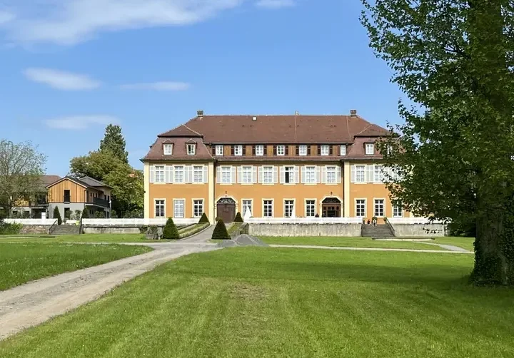 historisches-backsteingebaeude-gruene-wiese-blauer-himmel-park