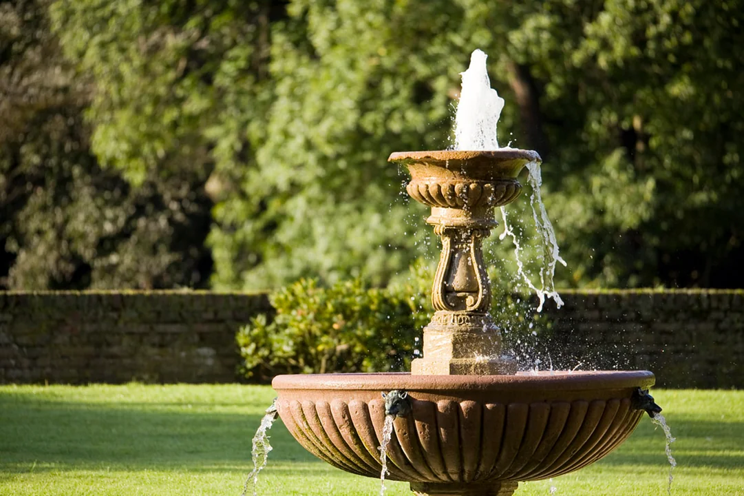 klassischer-steinbrunnen-garten-wasserspiel-sonnenlicht