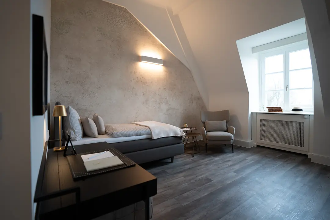 modernes hotelzimmer bett sessel holzboden wandleuchte