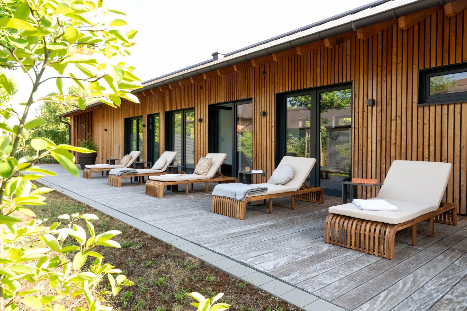 Terrasse mit Liegestühlen vor einem Holzgebäude im Garten von Schloss Freudental
